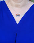 Person wearing a blue dress with an agate butterfly-shaped necklace