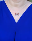 Sterling silver agate butterfly pendant necklace with orange, brown, and black hues, worn on a blue top.