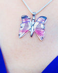 Butterfly-shaped agate silver necklace on a person's neck with a blue background