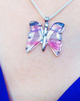 Butterfly-shaped agate silver necklace on a person's neck with a blue background