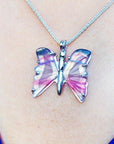 Butterfly-shaped agate silver pendant necklace on a chain against a skin background