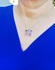 Sterling silver butterfly agate pendant necklace with rich pink wings on a woman's blue top.