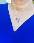 Sterling silver butterfly agate pendant necklace with rich pink wings on a woman's blue top.