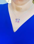 Sterling silver butterfly agate pendant necklace with rich pink wings on a woman's blue top.