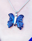 Dark blue natural agate butterfly pendant with silver setting on a silver chain, worn on a person.
