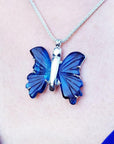 Dark blue natural agate butterfly pendant with silver setting on a silver chain, worn on a person.