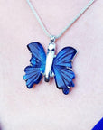 Dark blue natural agate butterfly pendant with silver setting on a silver chain, worn on a person.