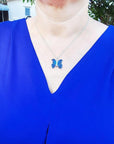 Dark blue natural agate butterfly pendant necklace with silver chain on a woman's neck.