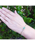 14K yellow gold bracelet with emerald-cut Colombian emerald and diamond accents on a woman's wrist.