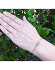 14K yellow gold bracelet with emerald-cut Colombian emerald and diamond accents on a woman's wrist.
