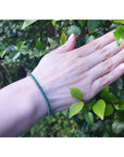 Natural Colombian emeralds tennis bracelet, round cut, medium deep green, 14K gold, on a woman's wrist.