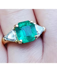Anillo con esmeralda certificada y diamantes triangulares en cada lado en oro amarillo de 18k.