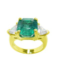 Anillo para mujer con esmeralda certificada por GIA y diamantes naturales de talla trillion en cada lado en oro de 18k amarillo.