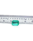 Square Muzo mine loose colombian emerald, fron position table and crown visibles whit a ruler measurer