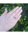 Asscher cut blue sapphire ring with halo diamonds in 18k white gold on a hand.