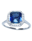 Asscher cut blue sapphire ring for women 18k white gold, sparkling medium dark blue color prong set with halo natural diamonds.