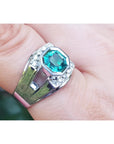A men's asscher cut natural colombian emerald ring crafted in 18k white gold worn on a finger.