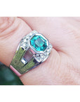 A men's asscher cut natural colombian emerald ring crafted in 18k white gold worn on a finger.