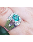 A men's asscher cut natural colombian emerald ring crafted in 18k white gold worn on a finger.