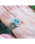 Men's 18K white gold ring with a vibrant bluish-green asscher-cut emerald and side diamonds.