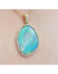 A close-up of an opal pendant necklace on a person's neck with a skin background.