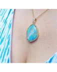 Opal pendant necklace on a person wearing a blue and white patterned top.