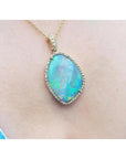 Opal pendant necklace on a person's neck with a pink skin background.