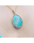 12.16 ct Australian opal pendant with bluish-green play-of-color, set in 18K yellow gold with diamonds.