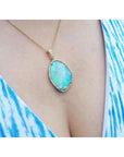 Opal necklace with gold chain on a person wearing a blue and white patterned top.