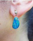 Australian opal doublet dangle earring in 14K yellow gold, featuring a vibrant blue and green opal in a bezel setting.