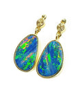 Vibrant blue Australian opal doublet dangle earrings in 14K yellow gold with bezel settings.