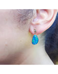 Australian opal doublet dangle earring in 14K yellow gold with bezel setting, worn on an ear.