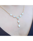 Handcrafted 14K yellow gold necklace with multiple teardrop and oval Australian opals on a woman's neck.