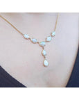 Handcrafted 14K yellow gold necklace with multiple teardrop and oval Australian opals on a woman's neck.