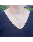 Handcrafted 14K yellow gold necklace with five solid Australian opals, three teardrop, two oval, on a woman's neck.