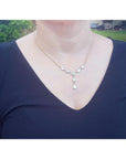 Handcrafted 14K yellow gold necklace with five solid Australian opals, three teardrop, two oval, on a woman's neck.