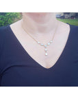Handcrafted 14K yellow gold necklace with five solid Australian opals, three teardrop, two oval, on a woman's neck.