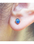 Close-up of an ear with a blue opal earring.