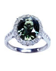 Oval bluish-green Australian sapphire ring with diamond halo and band in 18K white gold.