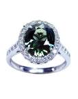 Oval bluish-green Australian sapphire ring with diamond halo and band in 18K white gold.