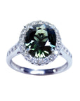 Oval bluish-green Australian sapphire ring with diamond halo and band in 18K white gold.