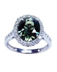Oval bluish-green Australian sapphire ring with diamond halo and band in 18K white gold.