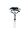 18K white gold ring with a large oval bluish-green Australian sapphire haloed by diamonds.