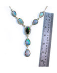 Necklace with opal stones next to a ruler for size reference on a white background