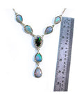 14k yellow gold Australian black opal necklace with diamond halo and teardrop opals, shown next to a ruler.