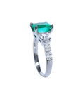 18K white gold ring with a cushion cut emerald and trapezoid side diamonds.