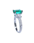 18K white gold ring with a cushion cut emerald and trapezoid side diamonds.