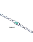 Back side of a 14K white gold paper clip bracelet with a medium deep bluish-green emerald.
