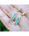 14K gold stud earrings with baguette-cut Colombian emeralds, pear-shaped extensions, and tapered baguette diamonds.