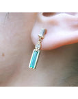 14K gold stud earring with baguette emerald, pear-shaped diamond, and tapered baguette diamond.